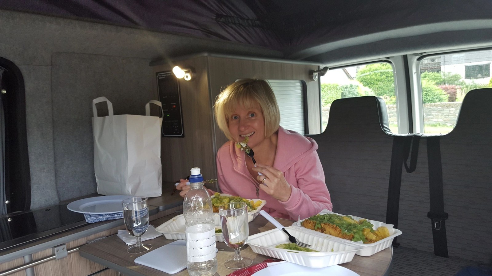 A woman enjoying lunch at a table inside a converted campervan