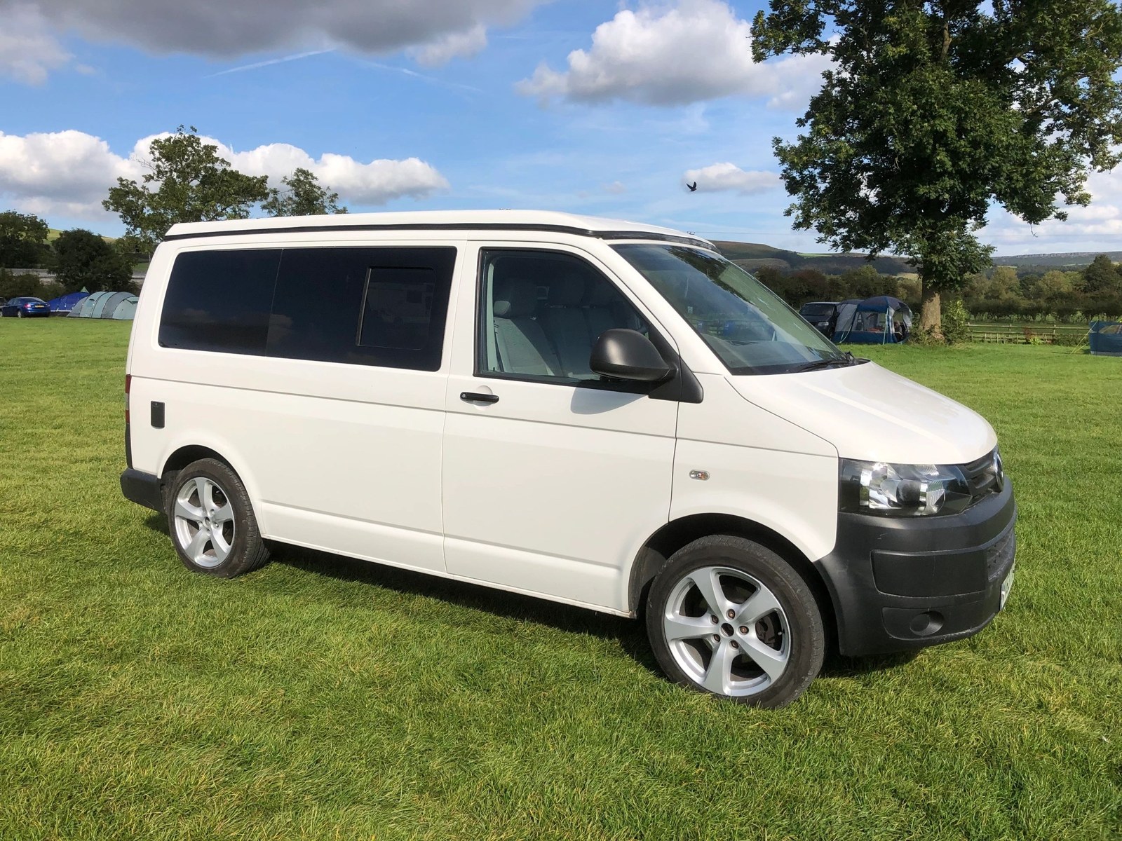 A completed white Volkswagen campervan parked on grass