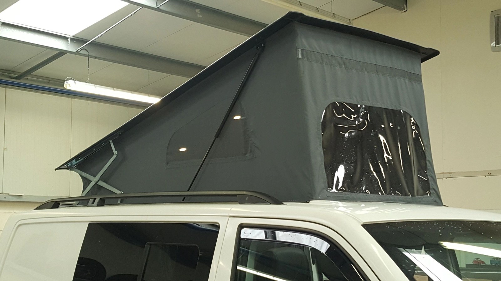 A raised pop-top roof fitted to a white campervan