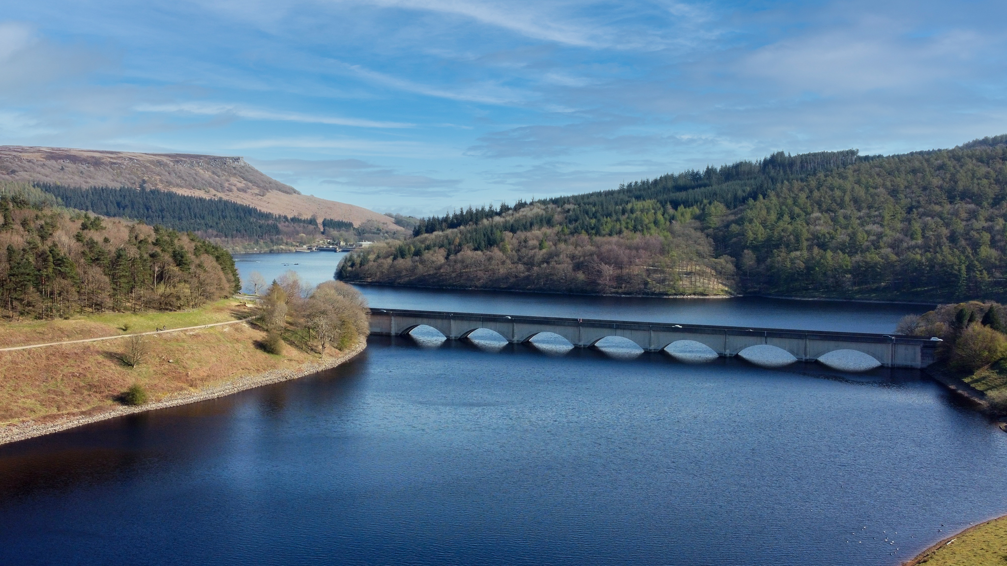 Sunshine over Ladybower Reservoir and Ashopton Viaduct beneath a blue Peak District sky