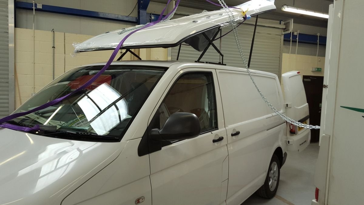 A white van with a roof frame raised above the cab