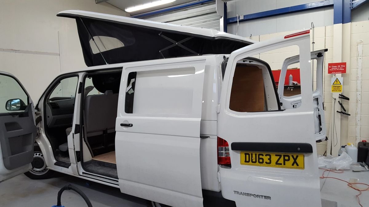 A white campervan with a pop-top roof being fitted