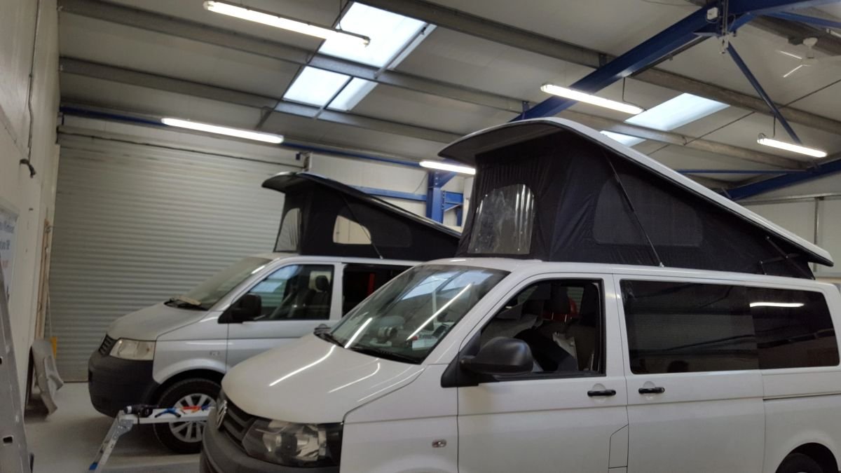 A finished white campervan with raised pop-top roof