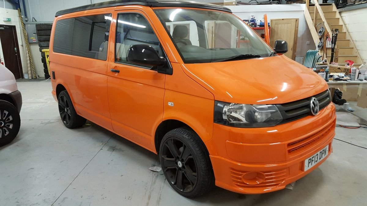 An orange Volkswagen van in the workshop